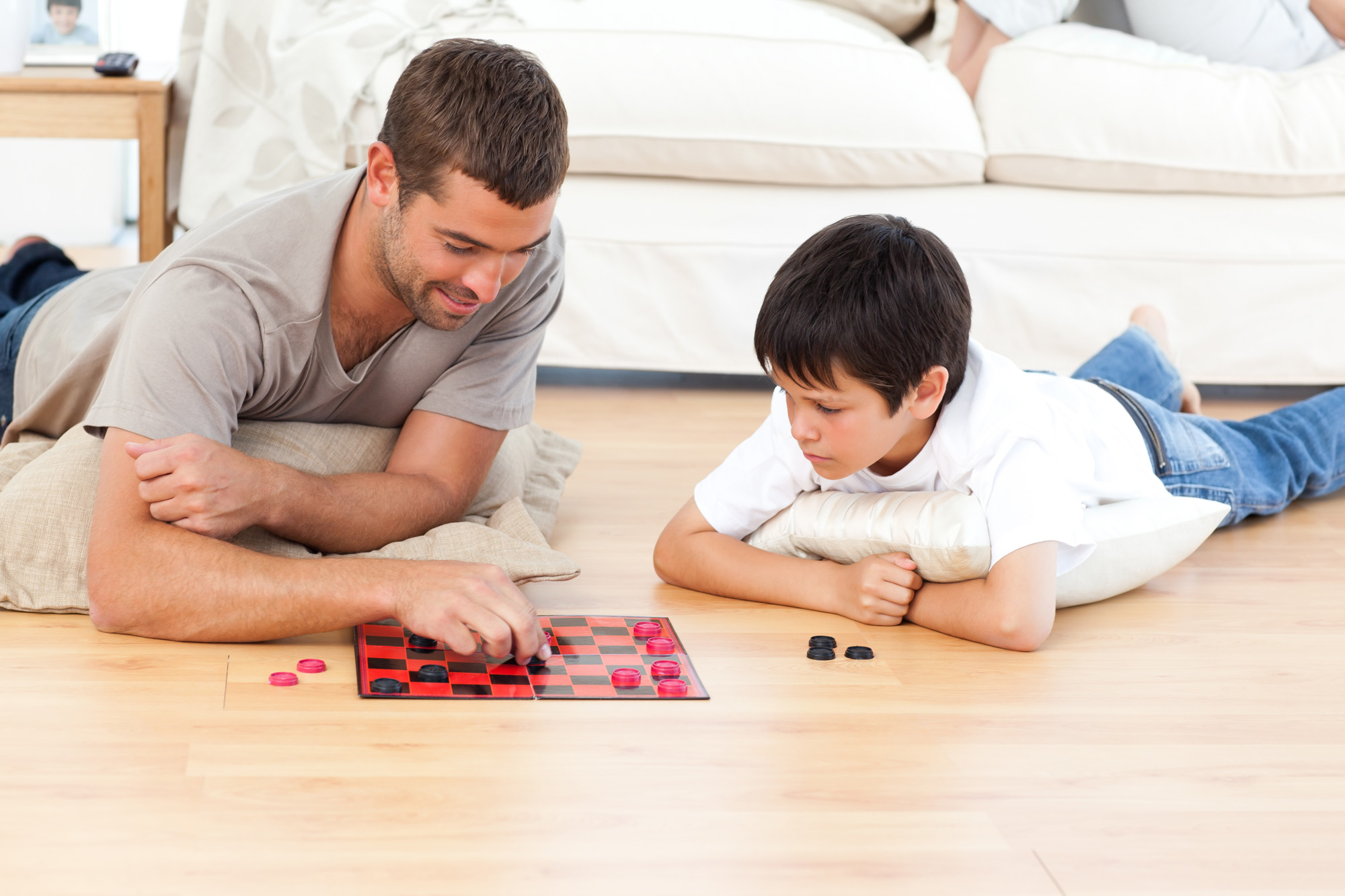 father and son playing checkers on laminate floor 